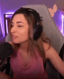 a woman wearing headphones is sitting in a gaming chair .