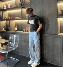 a man in a black shirt is leaning against a wall in a room
