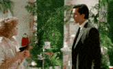 a man in a suit and tie is standing next to a woman in a bathroom holding a hair dryer