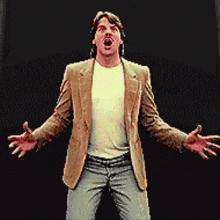 a man in a brown jacket and white shirt is standing with his arms outstretched