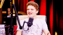 a young man is sitting in a chair in front of a microphone .