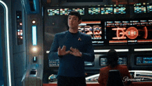 a man in a star trek uniform is standing in a room with a woman sitting in a chair .