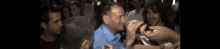 a man in a blue shirt is surrounded by a crowd