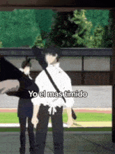 a man in a white shirt is standing in front of a building with the words yo el mas timido written on the bottom .