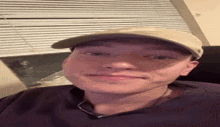 a young man wearing a baseball cap and a necklace is making a funny face .