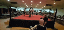 two men are wrestling in a ring with a referee watching