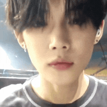 a close up of a person 's face with a gray shirt and earrings