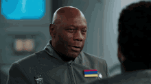 a man in a grey uniform has a rainbow colored ribbon on his collar