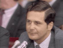 a man in a suit and tie is talking into a microphone