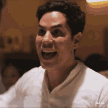 a man in a white shirt is smiling with his mouth open
