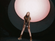 a woman with long blonde hair is standing in front of a pink light