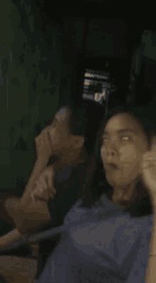 two women are sitting next to each other in a dark room and one of them is making a peace sign with her finger .