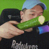a man wearing a black shirt that says radoukens is holding a cucumber