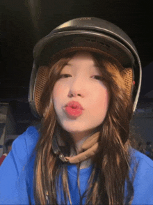 a girl wearing a helmet and a blue shirt is making a funny face