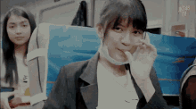 a girl wearing a mask is sitting next to a girl wearing a shirt that says jkt48