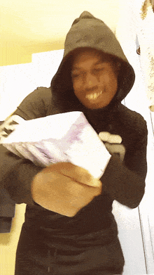 a man in a hoodie holds a stack of money in his hands