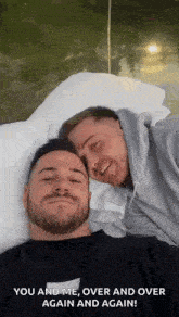 two men are laying on a bed with their heads together and smiling .