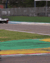 a race car is driving down a track with green and yellow lines