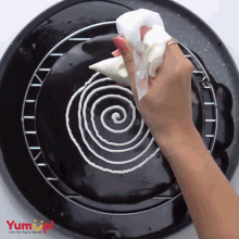 a person is frosting a cake with a swirl design and the words yum up behind them