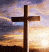 a cross with a sunset in the background and the sun shining through the clouds