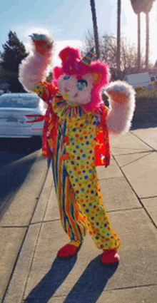 a stuffed animal dressed in a clown costume is standing on a sidewalk