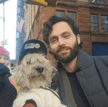 a man with a beard holds a small white dog in front of him