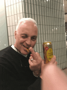 a man with a ring on his finger is holding a can that says ' ginger ale ' on it