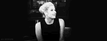 a black and white photo of a woman laughing in a chair .