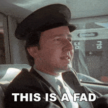 a man in a suit and hat is sitting in a car with the words " this is a fad " below him