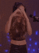 a woman wearing headphones and a crop top stands in front of a microphone