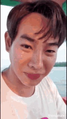 a close up of a young man 's face with a white shirt on
