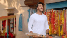 a man in a white shirt is holding a cricket bat with sg on it
