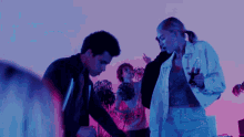 a group of people are dancing in a room with purple and blue lights