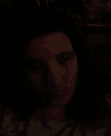 a woman 's face is shown in the dark with a statue in the background