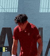a man in a red shirt stands in front of a sign that says a