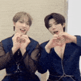 two men are making hearts with their hands