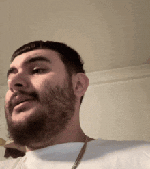 a man with a beard and mustache is wearing a white shirt and a gold chain around his neck