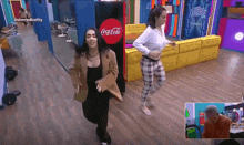 two women are dancing in front of a coca-cola vending machine
