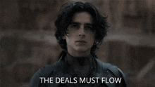a man holding a sword with the words " the deals must flow " below him