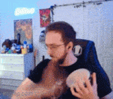 a man with glasses is sitting in a chair holding a tambourine .