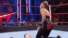 a woman is kneeling down in a wrestling ring while a crowd watches