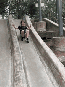 a young boy is sliding down a slide with his hands in the air