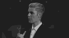 a black and white photo of a young man in a suit and tie .