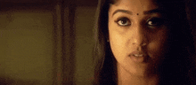 a close up of a woman 's face in a dark room with a blurred background .