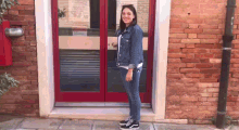 a woman is standing in front of a red door and smiling