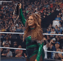 a woman in a green and leopard print wrestling outfit holds up a wrestling belt