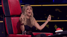 a woman is sitting in a red chair with a glass of water
