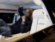 a man is laying in the back seat of a car with his hand on his head .