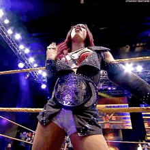 a woman in a wrestling ring with a belt around her waist