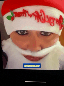 a close up of a person wearing a santa hat and beard with a christmas cover in the corner
